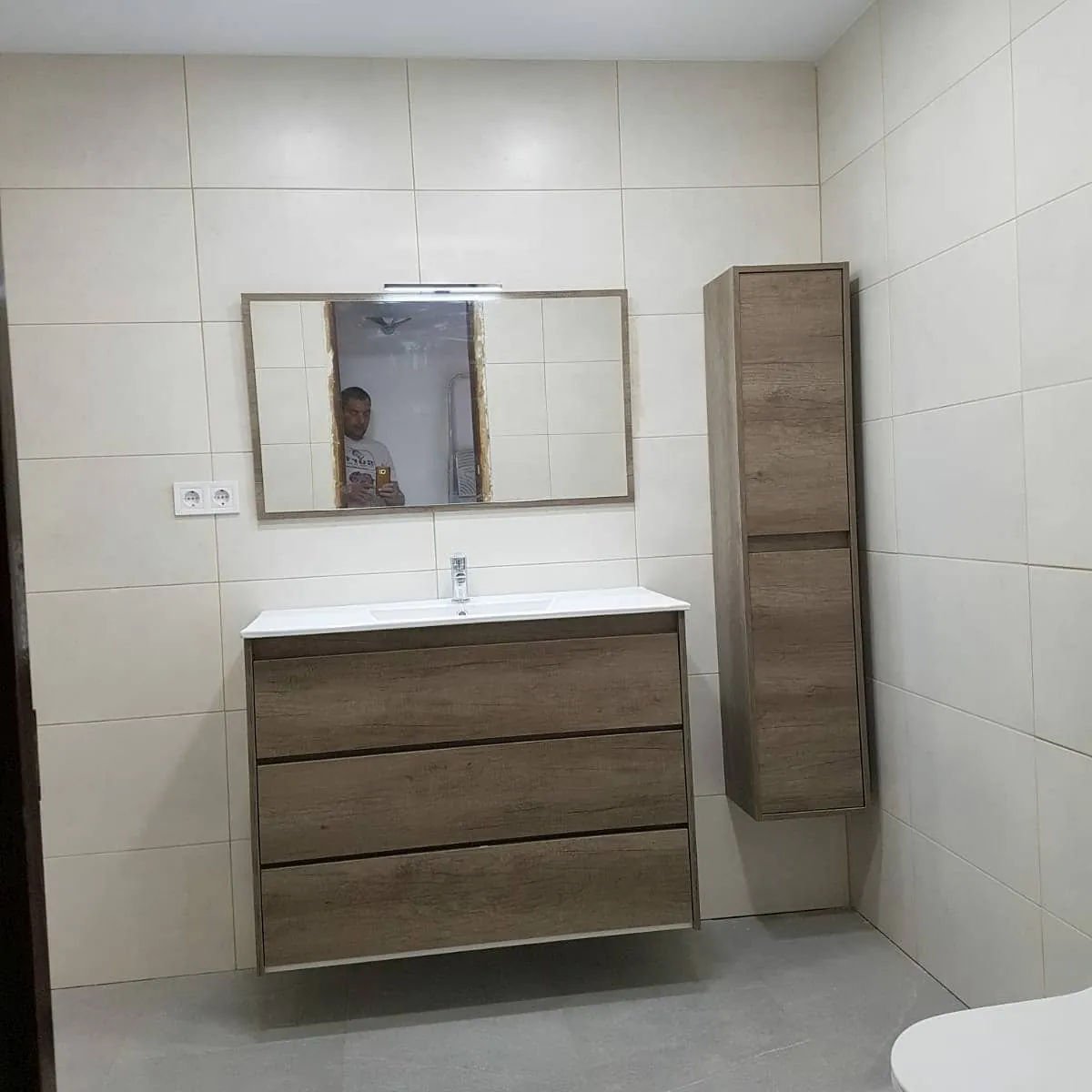 Baño en tonos claros con mueble y columna de madera
