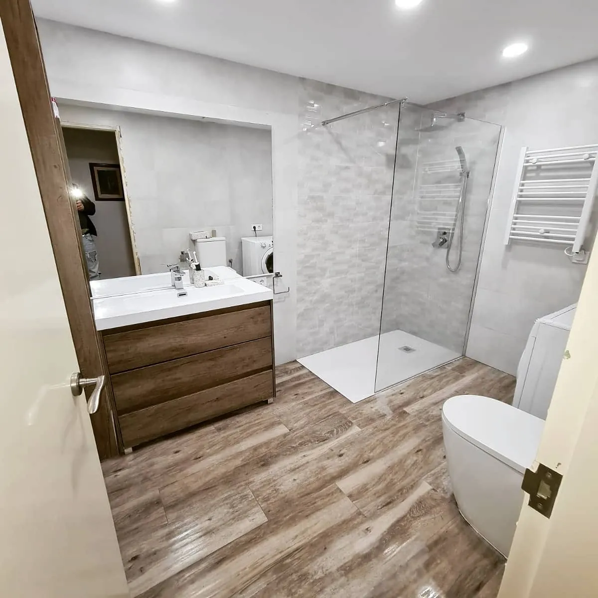 Después: Baño reformado: ducha a nivel de suelo con mampara fija, suelo porcelánico efecto madera y mueble suspendido