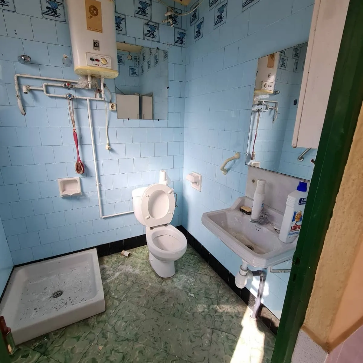 Antes: Baño antiguo renovado por completo: ducha con mampara corredera, mueble suspendido blanco y suelo efecto madera