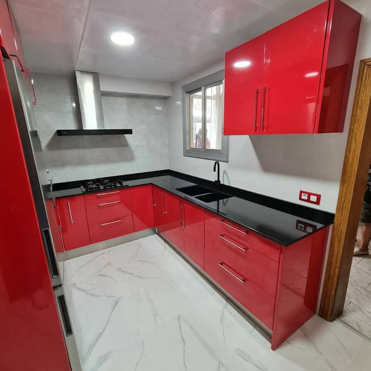 Cocina en U con frentes rojo brillo y encimera negra