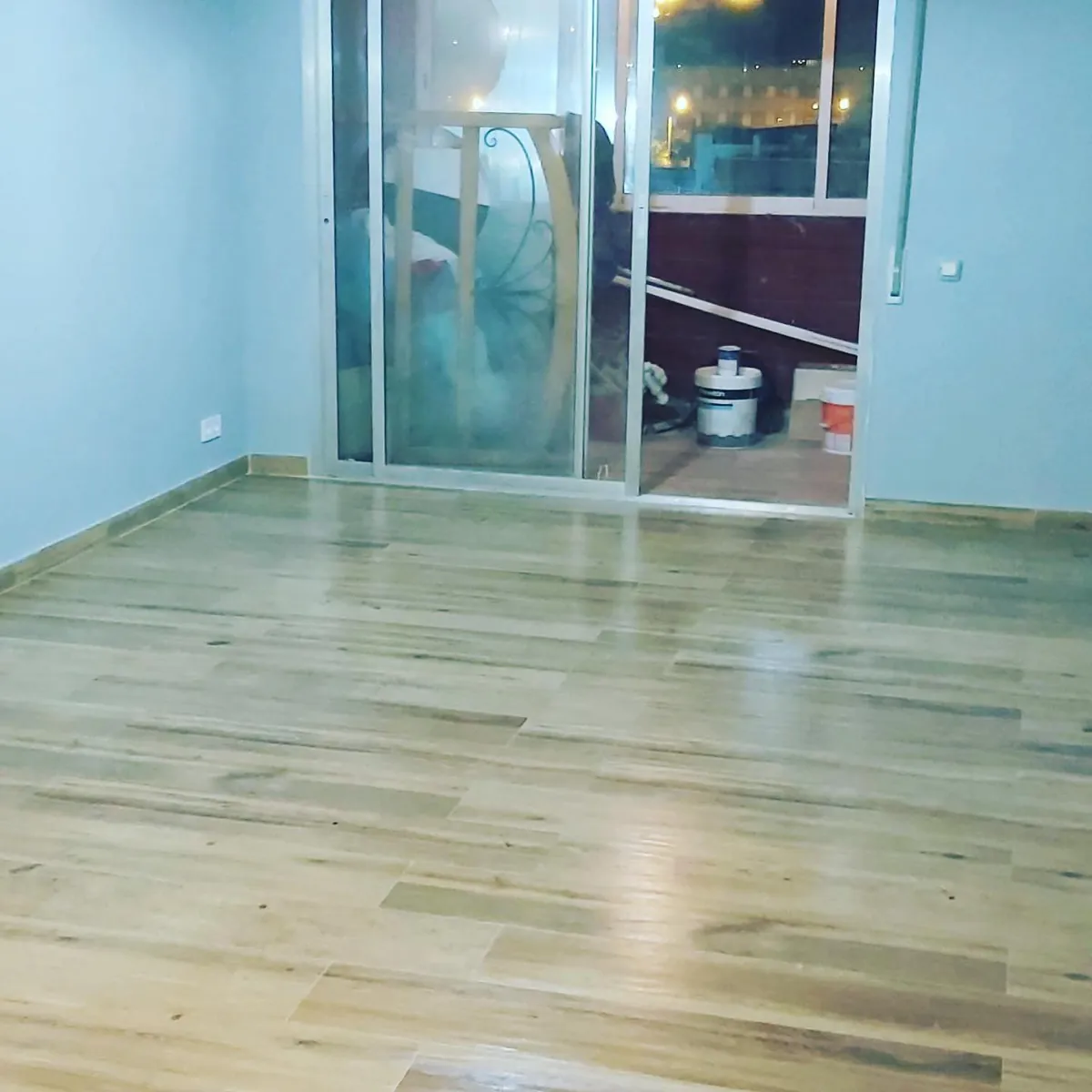 Salón con parquet y cerramiento de vidrio a la galería